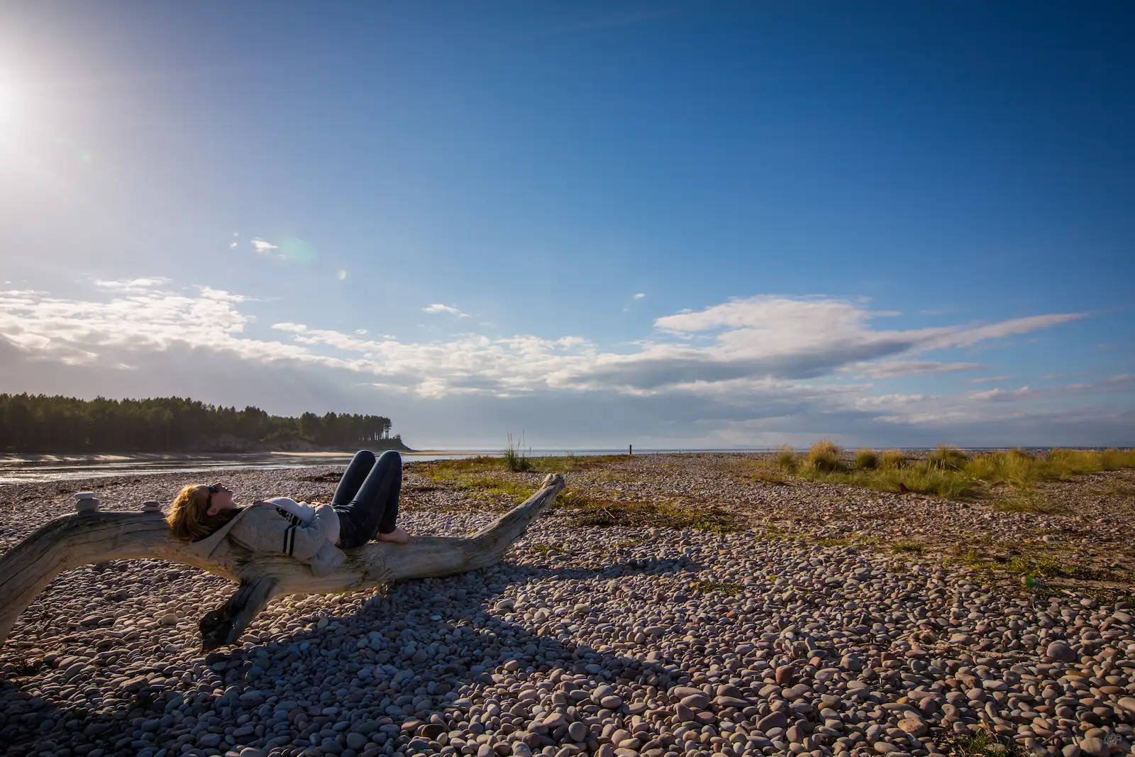 Clemmie Hopkinson relaxing on driftwood, demonstrating the Alexander Technique's connection to natural movement and ease